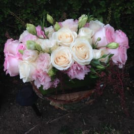 Pink and white rose bouquet with pale blooms in a low container