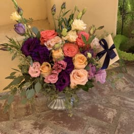 Mixed bouquet of roses and lisianthus in a silver vase with a ribbon