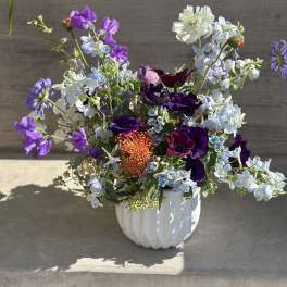 Mixed purple and white flowers arranged in a white vase
