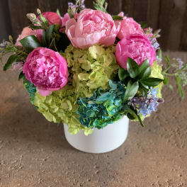 Pink peonies and hydrangeas arranged in a white vase