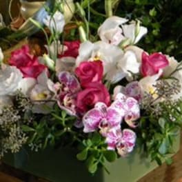 Pink and white floral arrangement in a green container