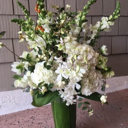 Tall white floral arrangement in a green vase