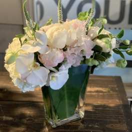 White and pale pink floral arrangement in a clear glass vase
