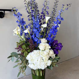 Tall blue and white floral arrangement in a glass vase