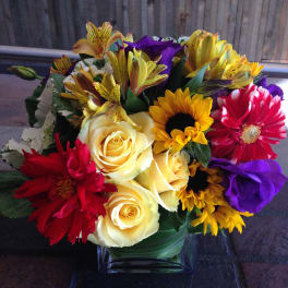 Mixed bouquet of roses, daisies, and alstroemeria in a glass vase