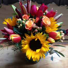Bright mixed bouquet with sunflowers, tulips, and peach roses in a vase