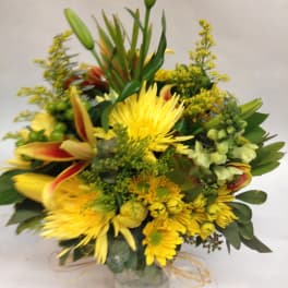 Yellow mixed flower bouquet in a clear glass vase