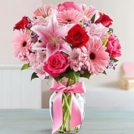 Pink and red mixed bouquet in a glass vase with a pink ribbon