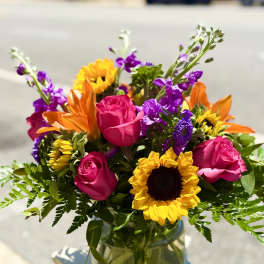 Bright mixed bouquet of roses and sunflowers in a glass vase