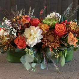 Mixed floral arrangement with roses, chrysanthemums, and white dahlias in a green container