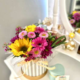 Bright mixed bouquet in a striped hatbox with a ribbon.