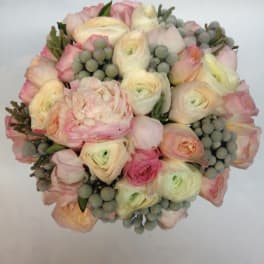 Round bouquet of pale pink and cream flowers with gray berry accents