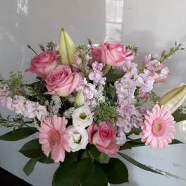 Pink and white mixed bouquet with roses, lilies, and daisies in a glass vase