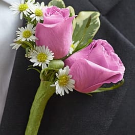 Pink rose boutonniere with small white daisies on a green stem wrap