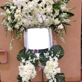 Large white funeral standing spray on an easel with orchids and roses