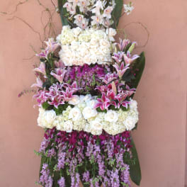 Tall standing floral spray with white roses, orchids, and pink lilies