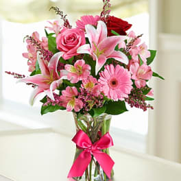 Pink and white mixed bouquet in a clear glass vase with a pink ribbon