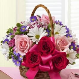 Basket of pink and red roses with white daisies and purple flowers