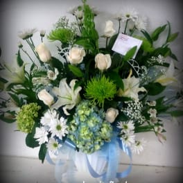 White roses and lilies with green and blue flowers in a ribboned bouquet