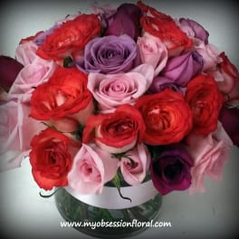 Bouquet of red, pink, and purple roses in a glass vase