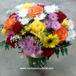 Mixed bouquet of roses, chrysanthemums, and daisies in a glass vase