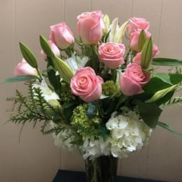 Pink roses and white lilies arranged with white hydrangea in a vase