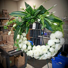 Large white floral wreath on an easel with green foliage and tulips