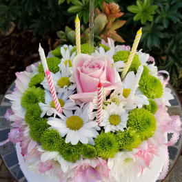 Round floral cake with pink rose, daisies, and striped candles