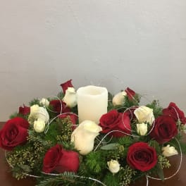 Red and white roses arranged around a white pillar candle