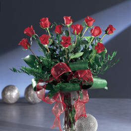 Red roses arranged in a clear glass vase with red ribbon
