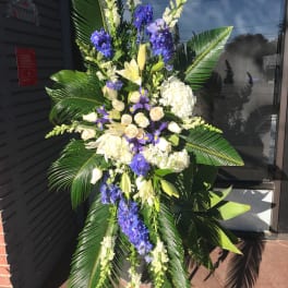 Tall standing floral spray with white and purple flowers and large palm leaves