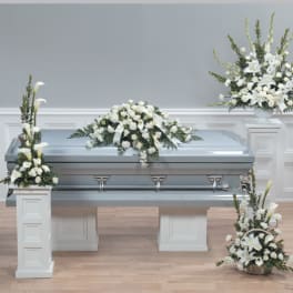 White funeral casket with white floral sprays and arrangements