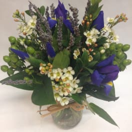 Blue iris bouquet with white blossoms in a glass jar