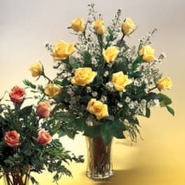 Yellow and peach roses in a clear glass vase with small white filler flowers