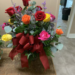 Mixed roses in a vase with a large red ribbon bow