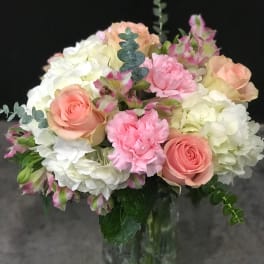 Bouquet of pink roses, white hydrangeas, and carnations in a glass vase