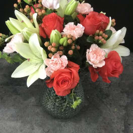 Bouquet of red roses, white lilies, and pink carnations in a glass vase
