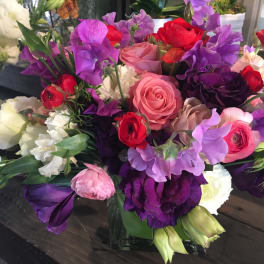 Mixed bouquet of pink, purple, red, and white flowers in a low vase