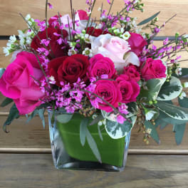 Pink and red roses arranged in a square glass vase