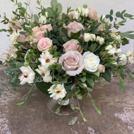 Pink and white roses in a clear glass vase with airy greenery