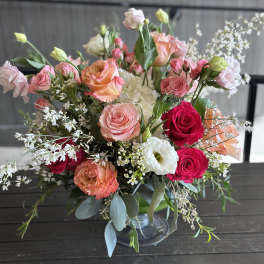 Mixed bouquet of pink, peach, and white roses in a glass vase