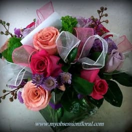 Bouquet of pink and peach roses with purple flowers and ribbon wrap