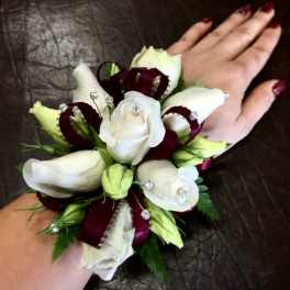 White rose wrist corsage with burgundy ribbon and rhinestone accents