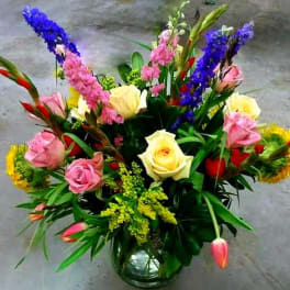 Mixed bouquet of roses and colorful tall blooms in a glass vase