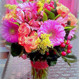 Bouquet of pink gerbera daisies and peach roses in a clear vase