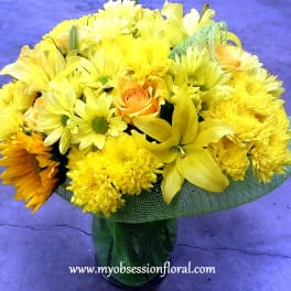 Yellow bouquet with daisies, chrysanthemums, and roses in a glass vase