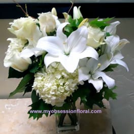 White lilies and roses arranged in a clear glass vase