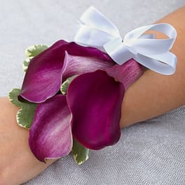 Purple calla lily corsage with a white ribbon on a wrist