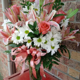 Pink roses and lilies with white daisies in a clear glass vase
