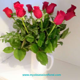 Red roses arranged in a white mug vase